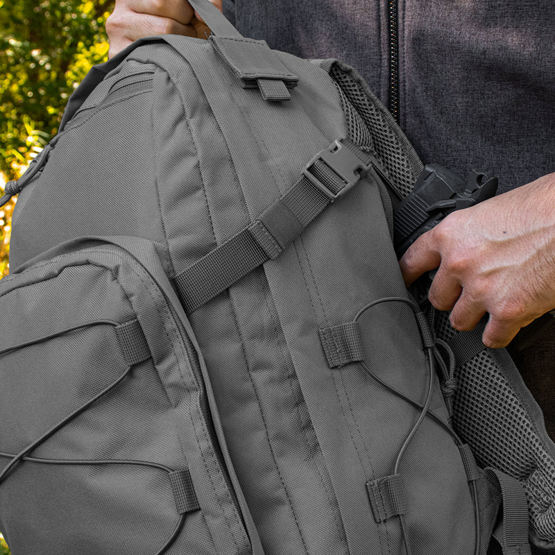 Person wearing a gray tactical backpack with a focus on the straps and design.