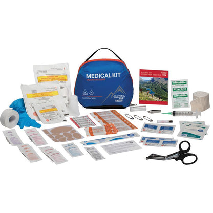 A comprehensive first aid and emergency medical kit laid out on a white background, featuring a blue and orange carrying bag, a blue glove, bandages, gauze, adhesive pads, a syringe, scissors, and instructional cards.